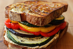 Vegan-friendly and nutritious sandwich featuring oven-roasted zucchini, eggplant, and bell peppers layered on hummus-spread whole grain bread.